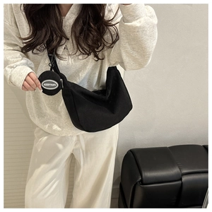 Detail of black corduroy crescent shoulder bag with small round coin purse attachment