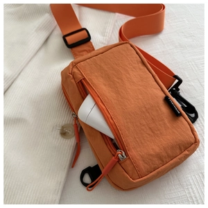 Internal storage detail of orange nylon crossbody bag with power bank inside