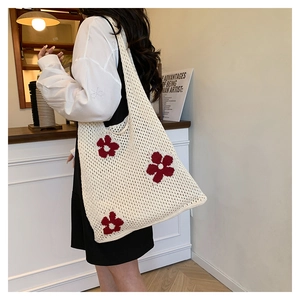 Detail of ivory crochet shoulder bag featuring red flower knit patterns for beach travel