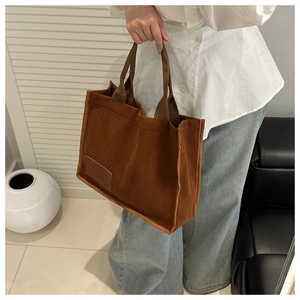 Close-up of brown corduroy tote bag showing striped texture and leather label detail