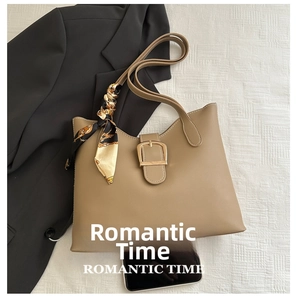 Khaki shoulder bag with silk scarf decoration and metallic clasp shown with a phone