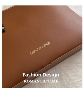 Détail de sac cabas en cuir marron avec logo doré et accessoire de foulard en soie
