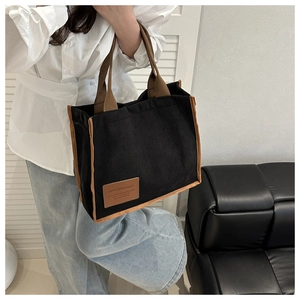 Detail of black corduroy tote bag with brown straps styled with a casual outfit