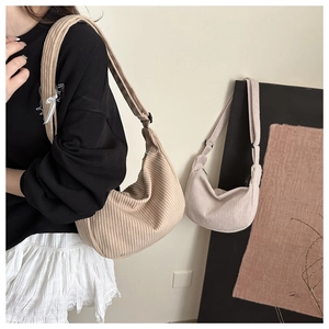 Detail of corduroy crescent crossbody bags in khaki and cream with adjustable straps