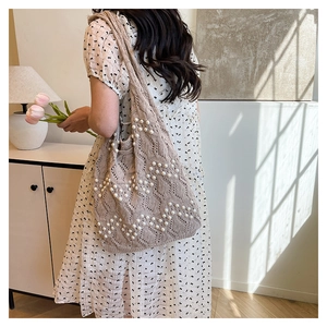 Detail of hand-woven tote bag with white pearl wave patterns on beige knit fabric