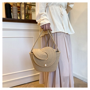 Close-up of handmade woven straw bag with pearl buckle on model in resort style