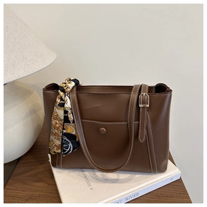 Detail of dark brown tote bag featuring white stitching and vintage floral scarf handle