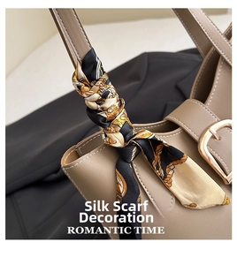Detail of a beige leather handbag handle wrapped with a yellow floral silk scarf and metal clasp