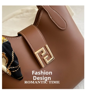 Detail of dark brown leather tote with white contrast stitching and gold metal buckle