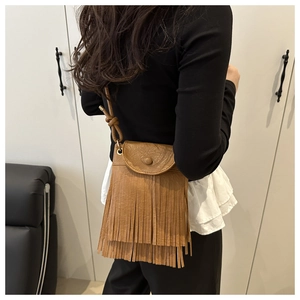 Brown fringe crossbody bag shown on a model featuring bohemian style tassels and faux leather