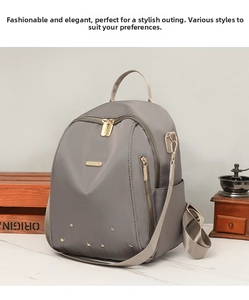 Détail d'un sac à dos gris en tissu Oxford avec rivets étoiles dorés et zips métalliques