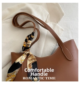Détail de la poignée d'un sac cabas en cuir marron ornée d'un foulard en soie
