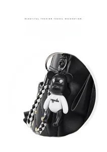 Detail of black quilted leather backpack featuring a stylish panda bear charm and woven strap