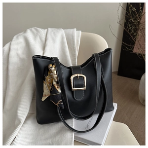 Detail of black leather tote bag with white stitching, gold buckle and printed silk scarf
