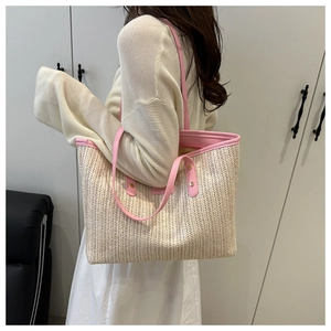 Détail du sac cabas en paille tressée avec anses en cuir rose et texture naturelle