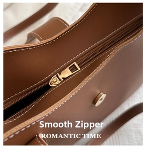 Macro detail of brown leather bucket bag featuring gold zipper and white contrast stitching