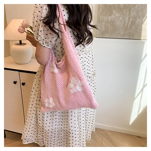 Detail view of pink crochet tote bag with white floral pattern and hollow knit texture