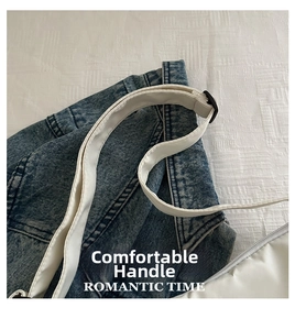 Detail of white canvas shoulder strap with black adjustable buckle over denim fabric