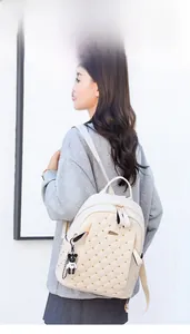 Quilted cream PU leather backpack with gold rivets and bear charm on female model