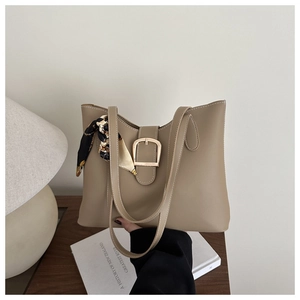 Detail of khaki PU leather tote bag featuring wavy top edge and silk scarf handle accent