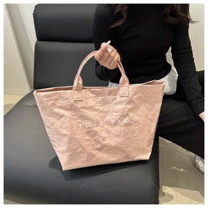 Detail of pink Tyvek tote bag with wrinkled texture and white TOTE BAG print