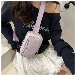 Detail of light purple nylon chest bag with dual zippers and adjustable fabric strap