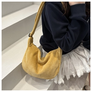 Detail of ginger yellow corduroy crescent bag showing soft ribbed texture and black strap