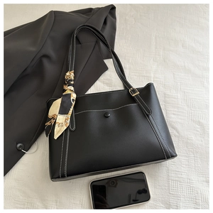 Detail of black tote bag featuring white contrast stitching and a decorative silk scarf