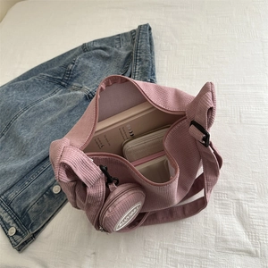 Pink corduroy hobo crossbody bag with coin purse and adjustable strap shown on denim jacket