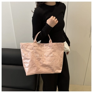 Close-up of pink tote bag featuring crinkled texture fabric and white TOTE BAG lettering
