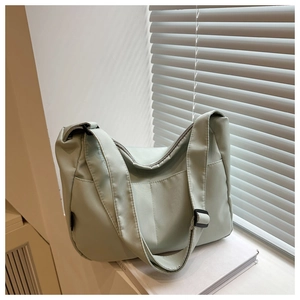 Detail of mint green nylon shoulder bag with adjustable strap on a window sill