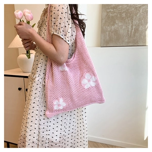 Détail du sac cabas rose en tricot avec motifs de fleurs blanches et design évidé