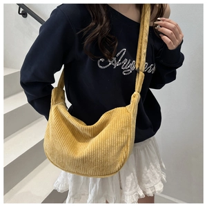 Model wearing a yellow corduroy crescent bag showing large capacity and soft texture
