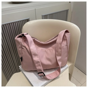 Detail of pink waterproof nylon tote bag with wide strap and front pockets for daily commute