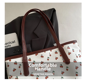 Détail du cabas blanc à motif cerises avec poignées et surpiqûres en cuir marron
