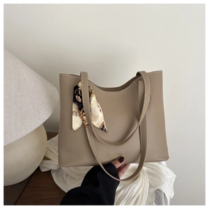 Detail of khaki leather tote with silk scarf accent and fashion lettering