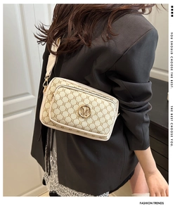 Close-up of vintage pattern shoulder bag with a gold M-logo and wide strap on model