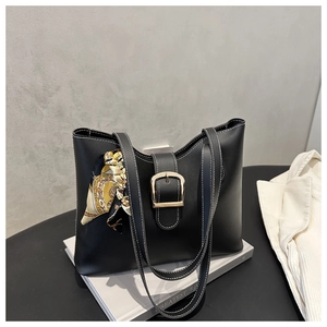 Close-up of black leather tote bag with white stitching and decorative silk scarf detail