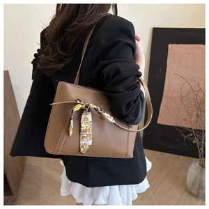 Detail of brown faux leather tote bag with silk scarf accessory and white contrast stitching