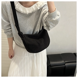Detail of black corduroy crescent crossbody bag showing textured fabric and adjustable strap