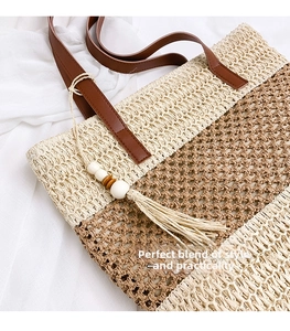 Detail of woven straw tote bag with brown leather handles and wooden bead tassels