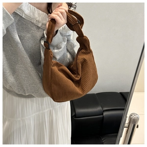 Detail of brown corduroy crescent bag with knotted strap and silver zipper closure