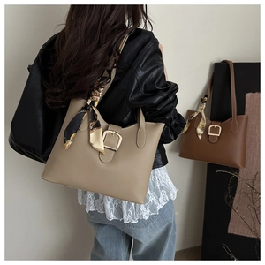 Detail of faux leather tote bag featuring metal buckle and decorative floral silk scarf