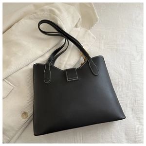 Detail of black leather tote bag with white contrast stitching and dual shoulder straps