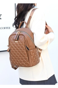 Rear view of model wearing brown quilted PU leather backpack with gold rivet accents