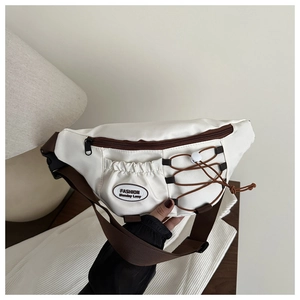 Détail du sac bandoulière blanc avec fermeture éclair marron et étiquette de mode