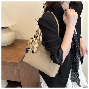 Detail of beige tote bag with smooth leather finish, snap pocket, and printed scarf handle