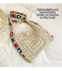 Top-down view of a beige crochet shoulder bag with colorful floral embroidery and straw hat