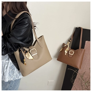 Detail of minimalist PU leather tote bag featuring gold buckle and floral silk scarf