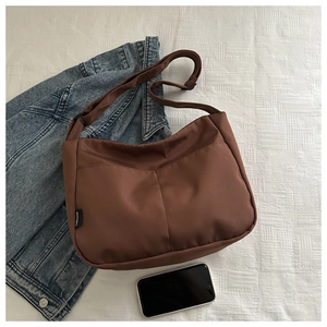 Detailed top view of large brown hobo tote bag on white fabric with denim jacket